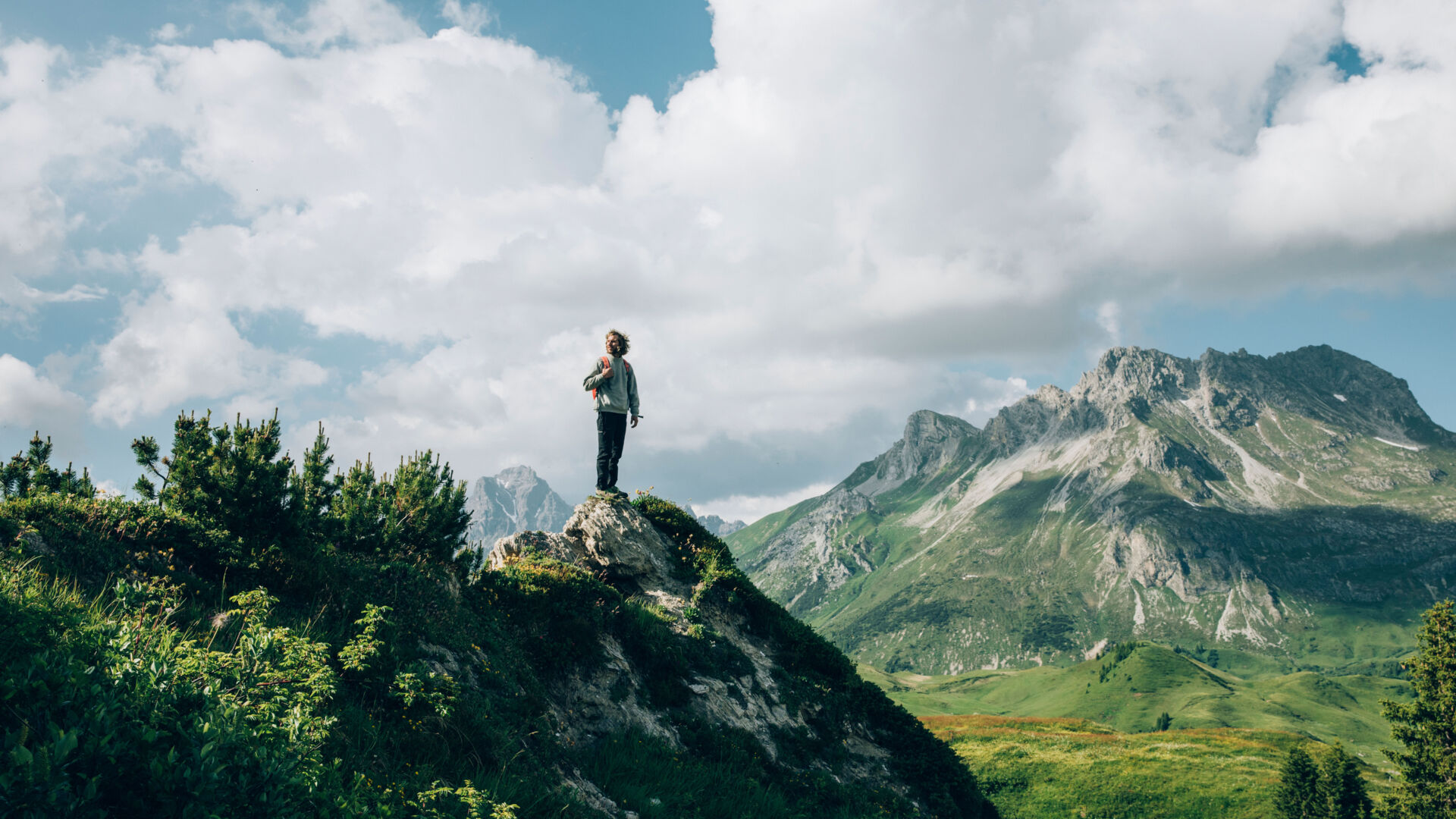 ein Wanderer steht auf einem Felsvorsprung und genießt die Aussicht auf die Gipslöcher und das traumhafte Bergpanorama im Hintergrund