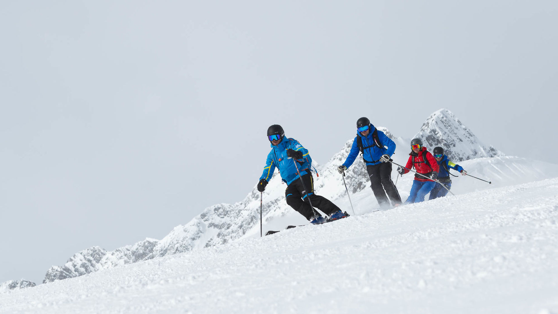 vier Skifahrer fahren über die Piste