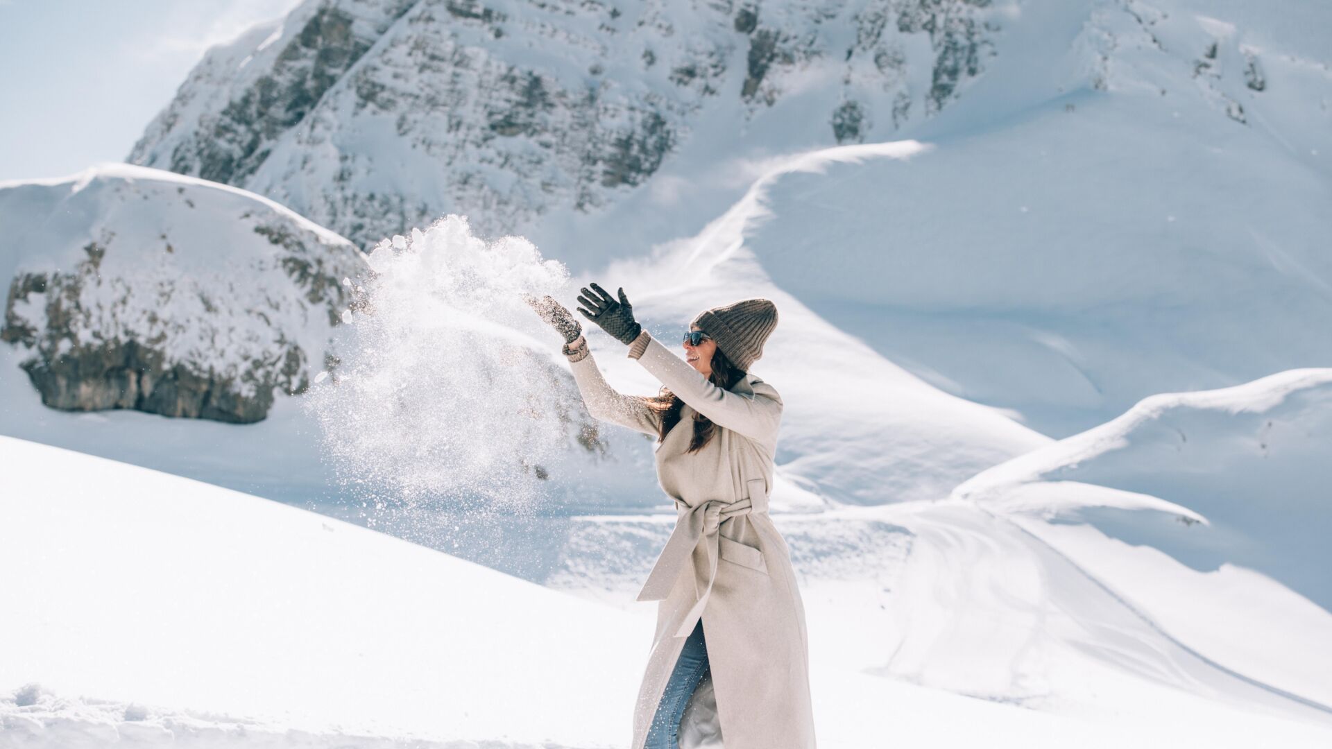 Eine Dame hat Spaß beim Winterwandern am Rüfikopf und wirft den Schnee hoch