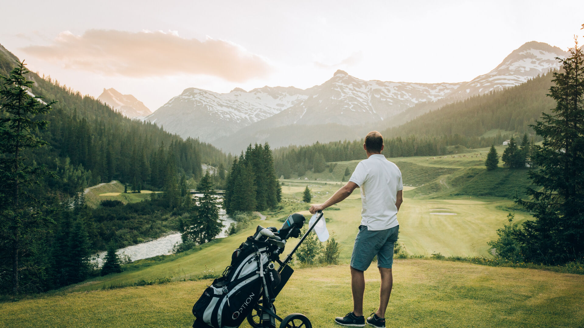 Golfer am Zuger Golfplatz sieht in die Ferne; im Hintergrund erstreckt sich der Lech sowie leicht angeschneite Berggipfel