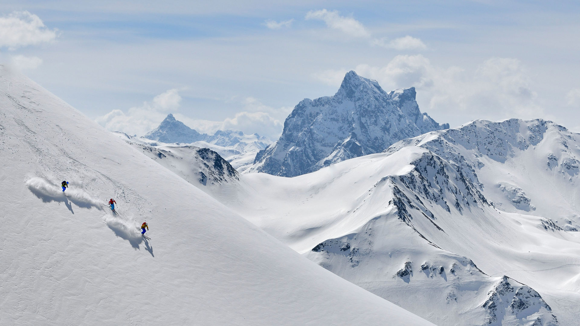Drei Skifahrer in der Abfahrt am Sonnenhang im Tiefschnee