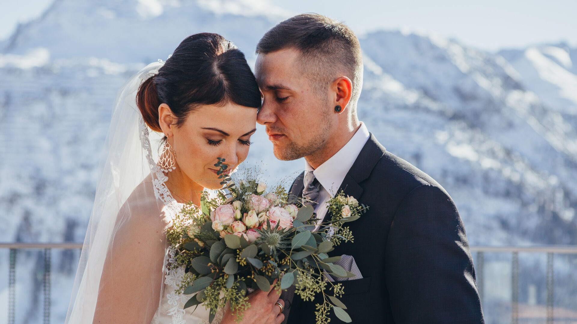ein romantischer Moment des Brautpaares vor der winterlich verschneiten Bergkulisse in Vorarlberg