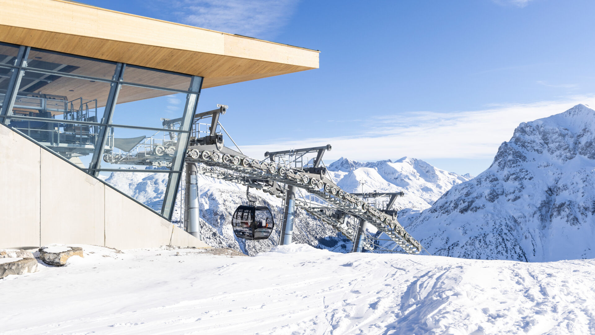 Blick auf die Bergstation der Zugerbergbahn, im Hintergrund ragen die verschneiten Berge hoch, bei malerisch sonnigem Wetter