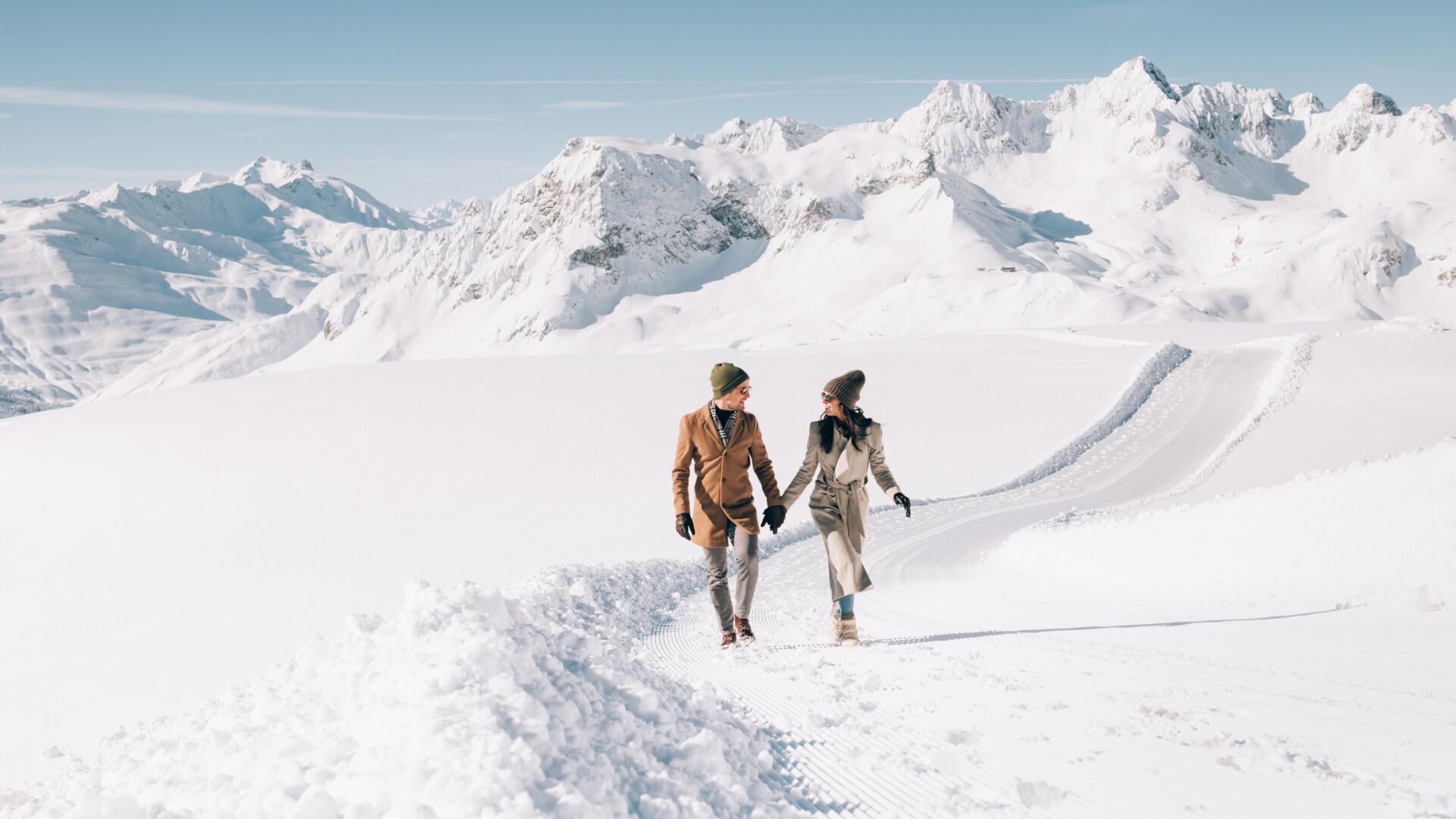 zwei Personen gehen über den Schneeflockenpanoramaweg am Rüfikopf bei Sonnenschein