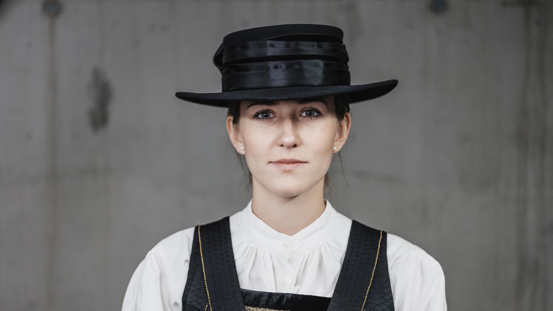 Frau in traditioneller Walsertracht mit schwarzen Hut, weißer Bluse und besticktem Kleid