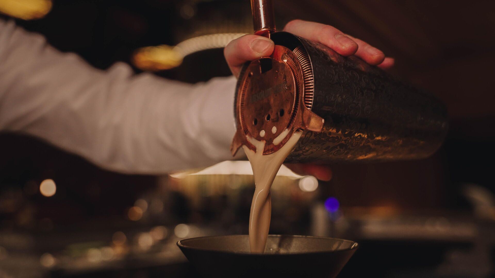 Ein Cocktail wird aus dem Shaker gegossen