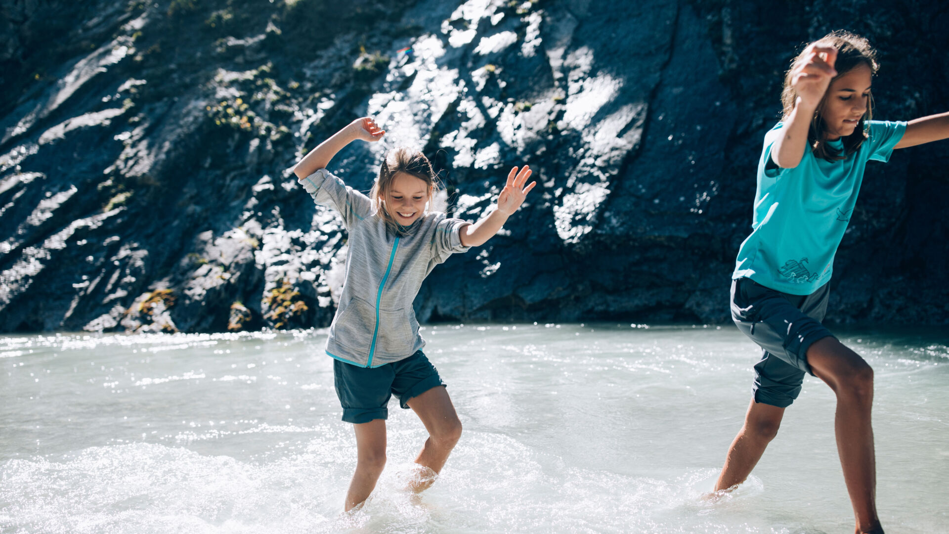 Zwei Kinder toben barfuss im Lech im Sommer