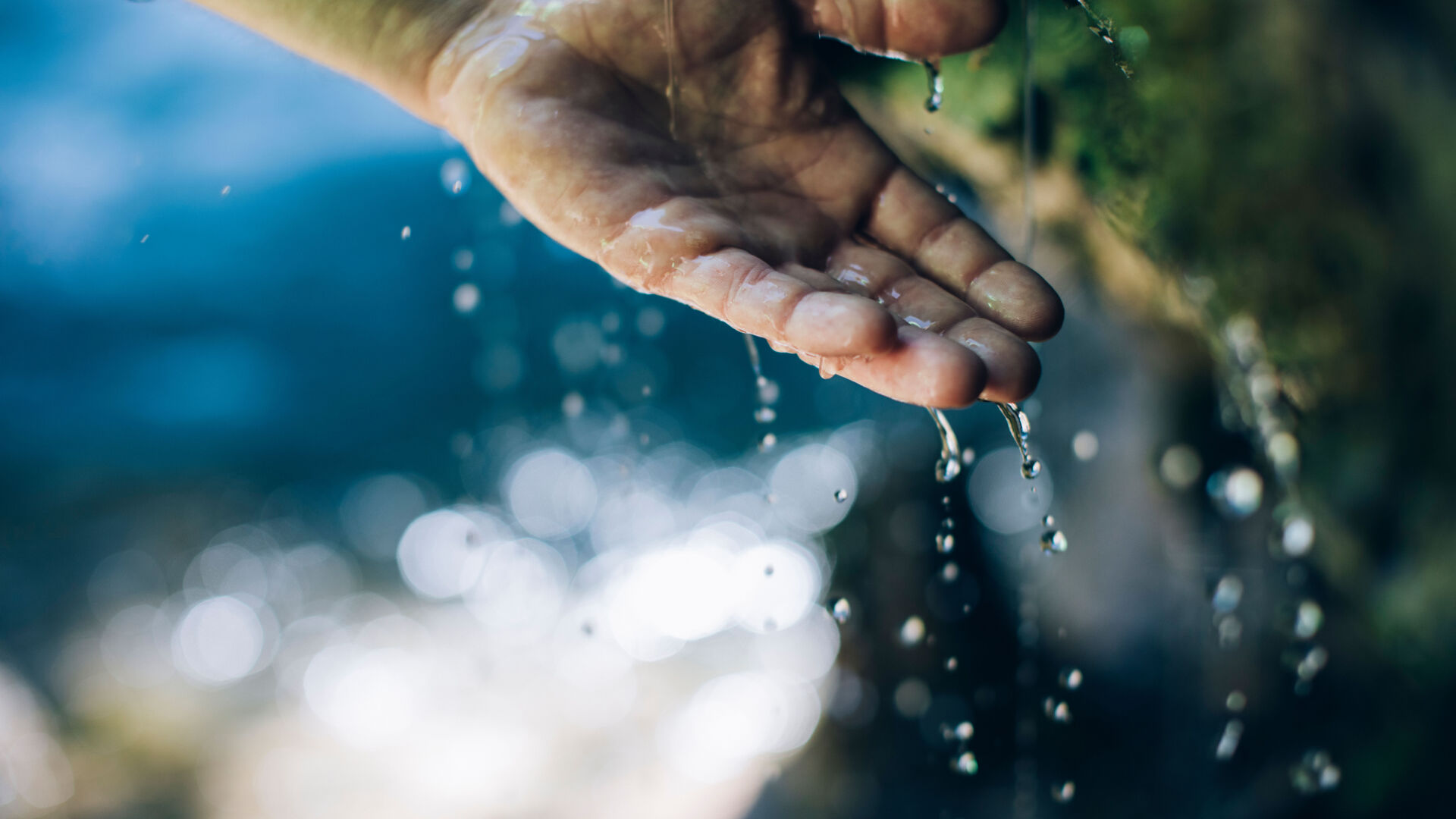 ein Mann hält seine Hand unter das plätschernde Wasser vom Wasserfall in Zug