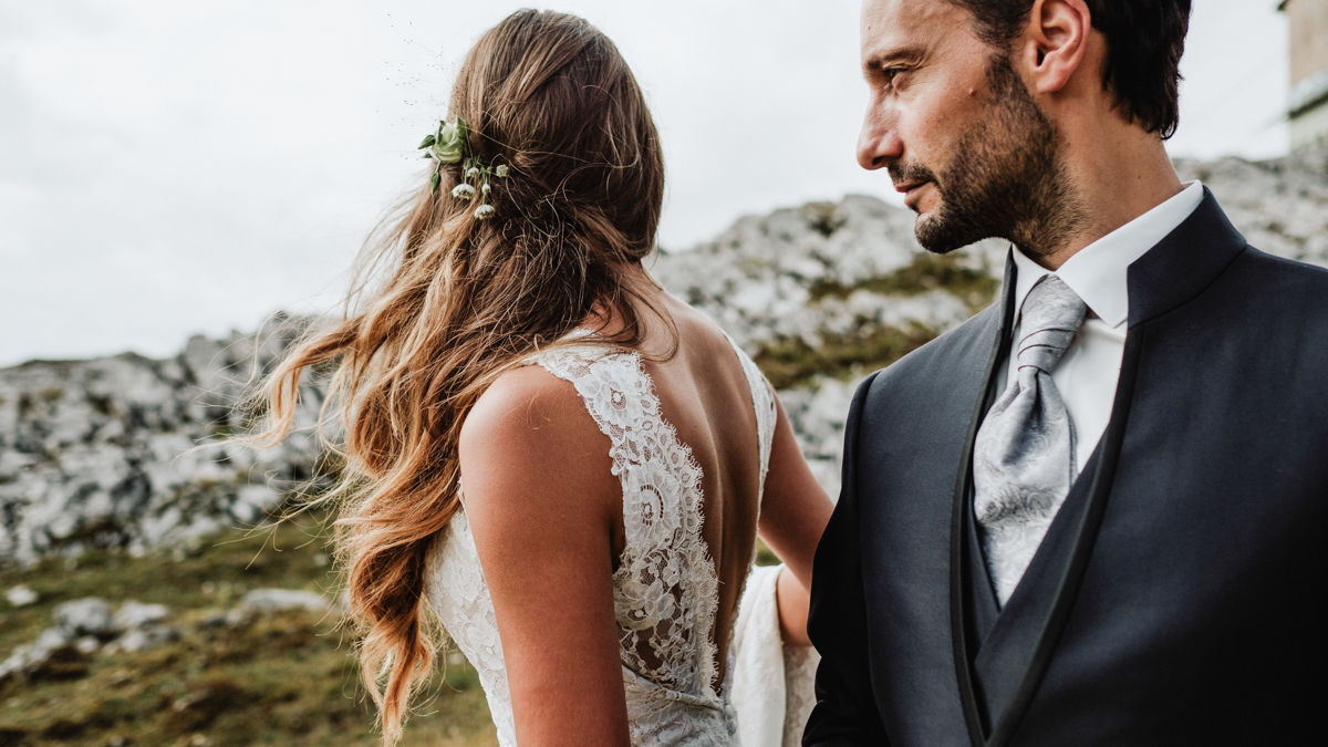 Hochzeitspaar in Nahportrait. Braut sieht man von hinten mit schönen langen Haaren und in Hochzeitskleid und Mann sieht man von der Seite mit Blazer und Kravatte.