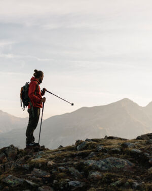 Ein Wanderer steht an einer Felskante und blickt auf das weitl&auml;ufige Bergpanorama. 