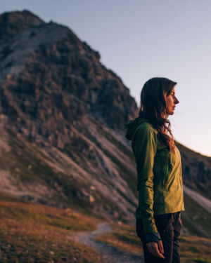 Wanderin steht am Berg in der Morgensonne und blickt in die Ferne