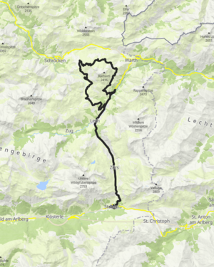 Drei Radfahrer fahren einen Schotterweg auf einen Berg hinauf. 