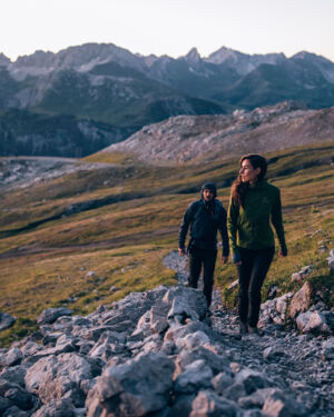 Eine Frau und ein Mann wandern auf einem Steig im Hochgebirge bei Sonnenaufgang