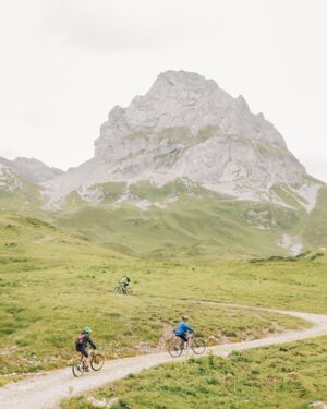 Drei Radfahrer fahren einen Schotterweg auf einen Berg hinauf.