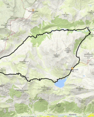 ein Wanderweg f&uuml;hrt durch die gr&uuml;nen Bergwiesen &uuml;ber dem Formarinsee vorbei