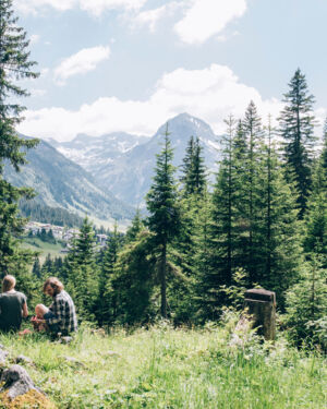 ein junges Paar macht eine Pause am Berg und genießt die Jause mit einer herrlichen Aussicht auf die Bergkulisse mit dem Omeshorn