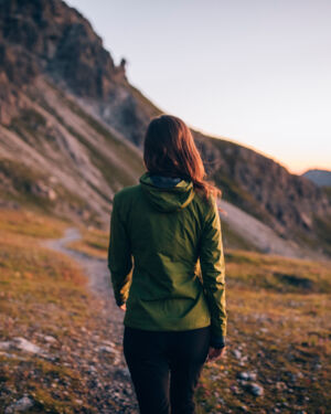 Frau wurde von hinten fotografiert wie sie an einem Steig bei Sonnenaufgang wandert