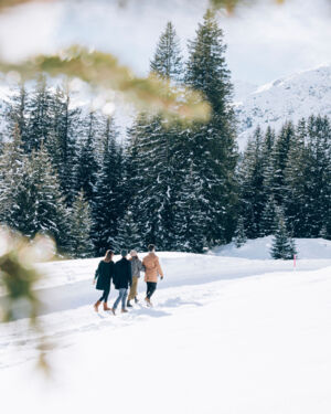 Freunde spazieren gemeinsam &uuml;ber den Winterwanderweg, im Hintergrund ist das atemberaubende Bergpanorama zu sehen