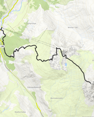 Wanderin steht am Berg in der Morgensonne und blickt in die Ferne