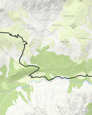 Eine Frau und ein Mann wandern bergauf w&auml;hrend im Hintergrund die Sonne &uuml;ber die Berggipfel scheint