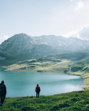 zwei Personen genießen die Aussicht auf den Formarinsee vor dem herrlichen Bergpanorama