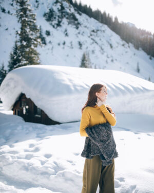eine Frau bleibt beim Winterwandern stehen und genie&szlig;t die ruhigen Momente in der winterlichen Landschaft von Lech Z&uuml;rs