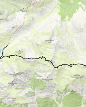 Eine Frau und ein Mann wandern bergauf während im Hintergrund die Sonne über die Berggipfel scheint