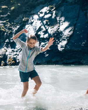 Zwei Kinder toben barfuss im Lech im Sommer