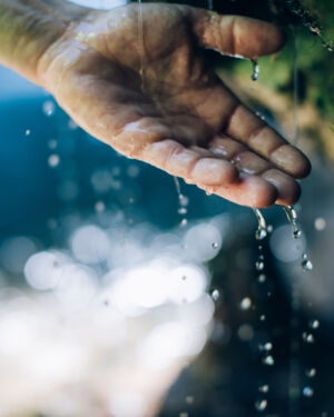 ein Mann hält seine Hand unter das plätschernde Wasser vom Wasserfall in Zug