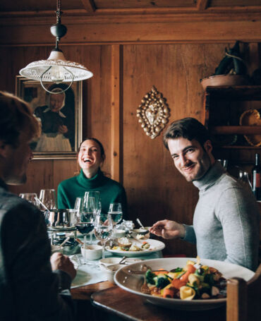 Freunde sitzen gemeinsam am runden Tisch und genießen freudige Momente beim Essen miteinander