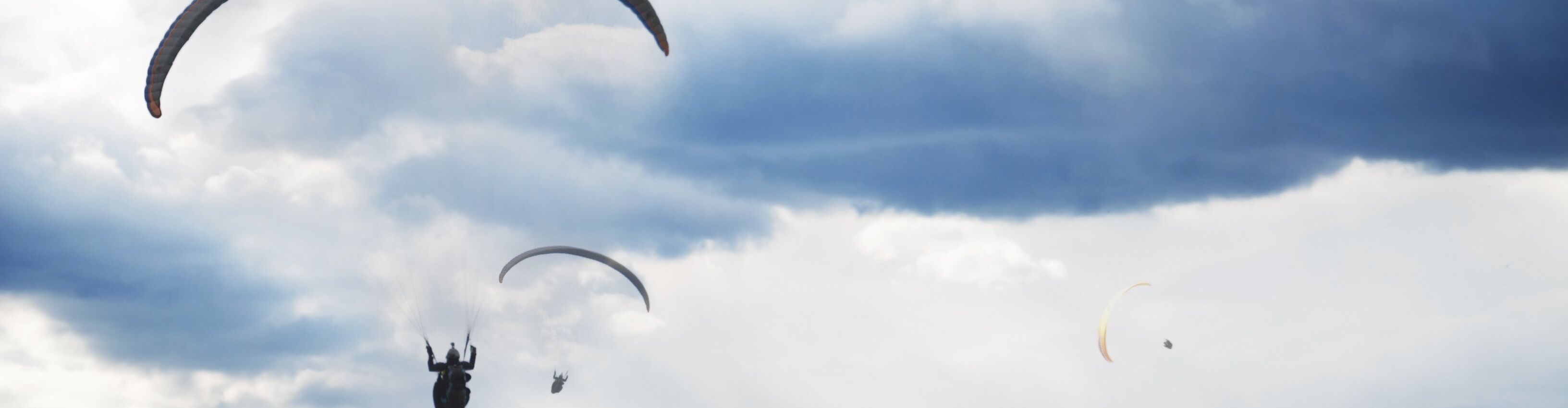 mehrere Tandemflieger fliegen durch die Wolkendecke