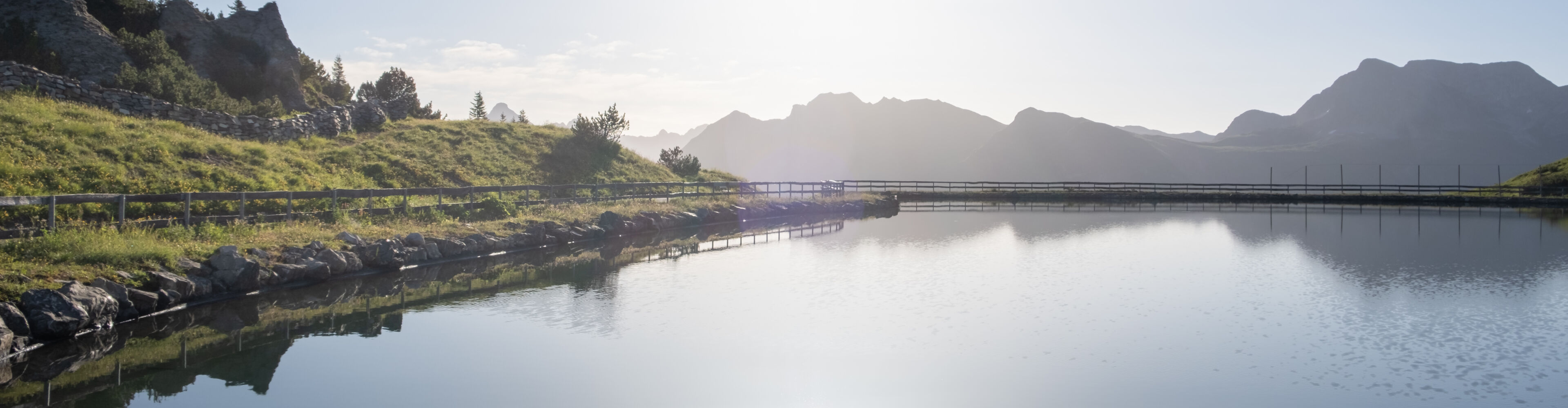 Blick über den Speichersee auf das weitläufige Bergpanorama
