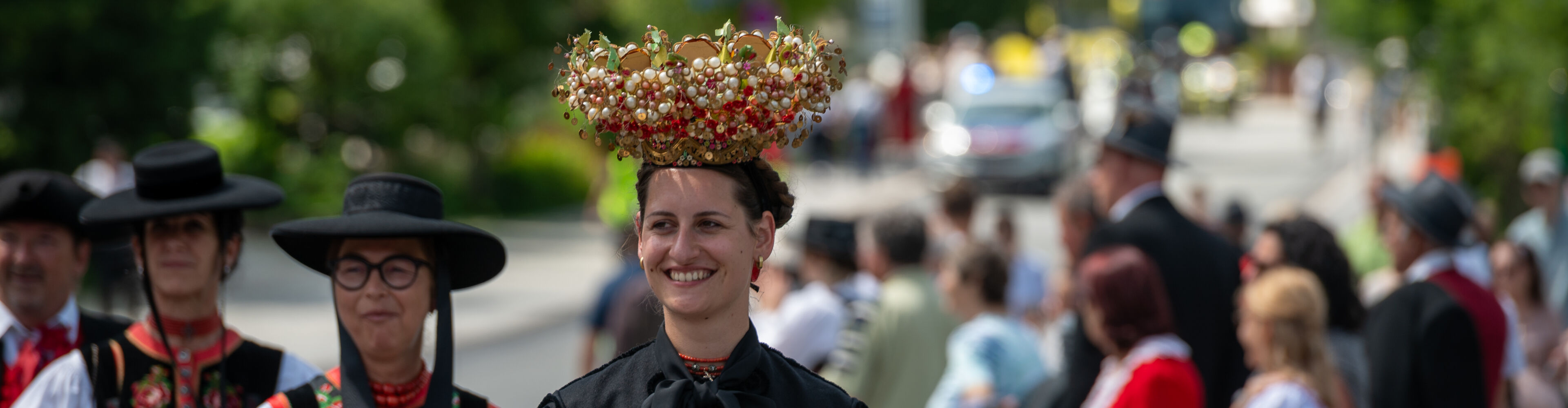 Teilnehmer:innen mit spezieller Tracht und Hüten die am Walsertreffen beim Umzug teilnehmen