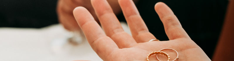 In einer offenen gehaltenen Hand liegen zwei Ringe die bereit sind angesteckt zu werden