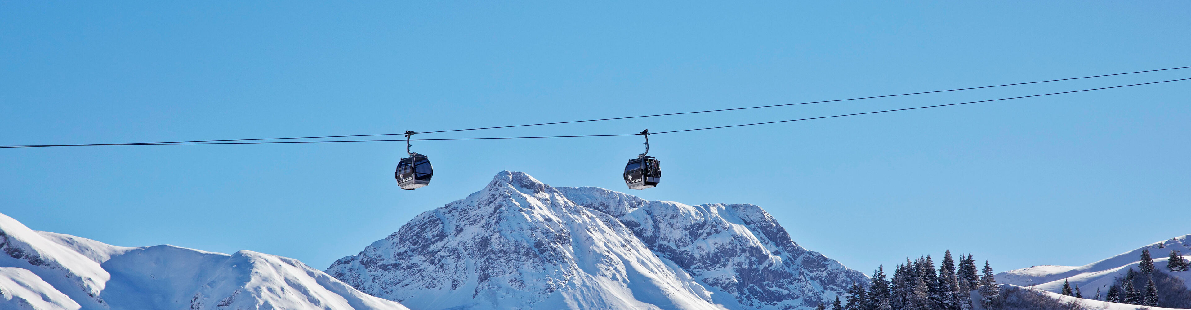 2 Gondeln des Auenfeldjet fahren über die malerische Bergkulisse im Winter in Lech Zürs