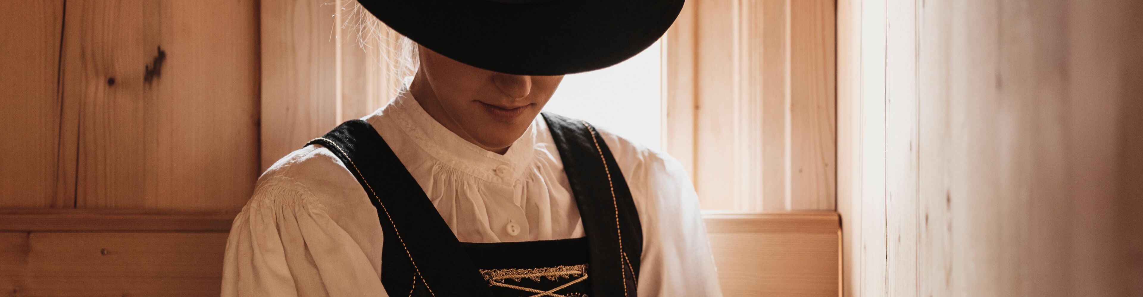 Frau in Walsertracht mit schwarzen Wollrock feines besticktes Samtband, Mieder, Schürze und Hut