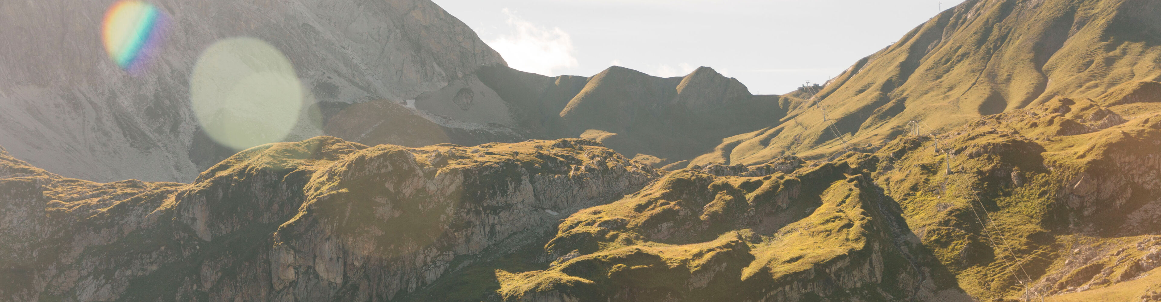 Weiläufiges Bergpanorama mit grünen Grashängen und kargen Felsen