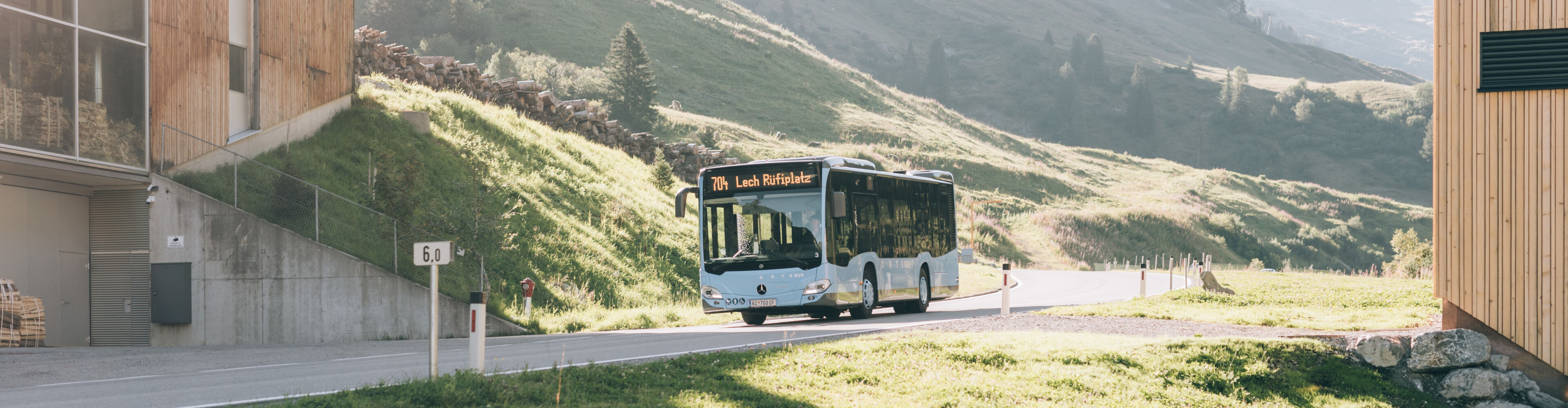 Blauer Ortsbus fährt im Sommer an der Hauptstraße von Zürs nach Lech