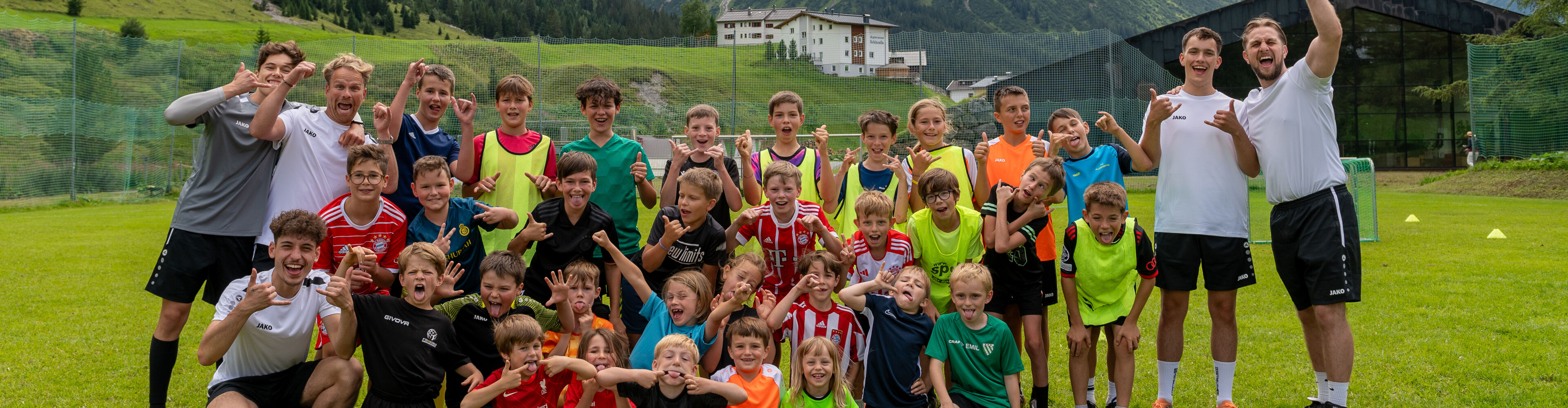 Mannschaft der Kindergruppe beim Fußballcamp mit den Trainern am Fußballplatz outdoor