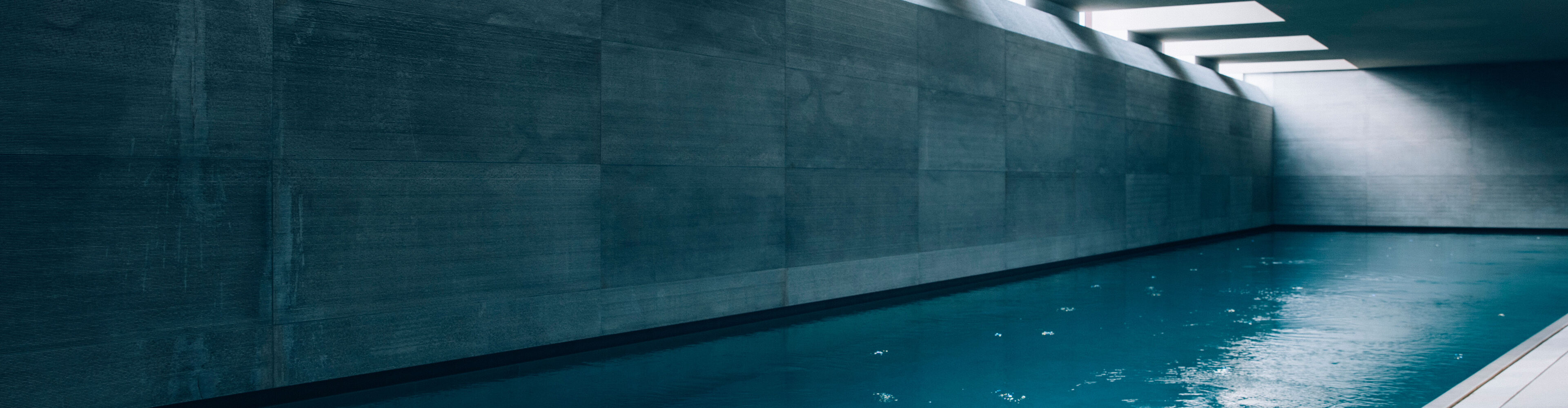 Dame entspannt in architektonisch ansehnlichen großen Indoor Pool mit Oberlichtfenstern