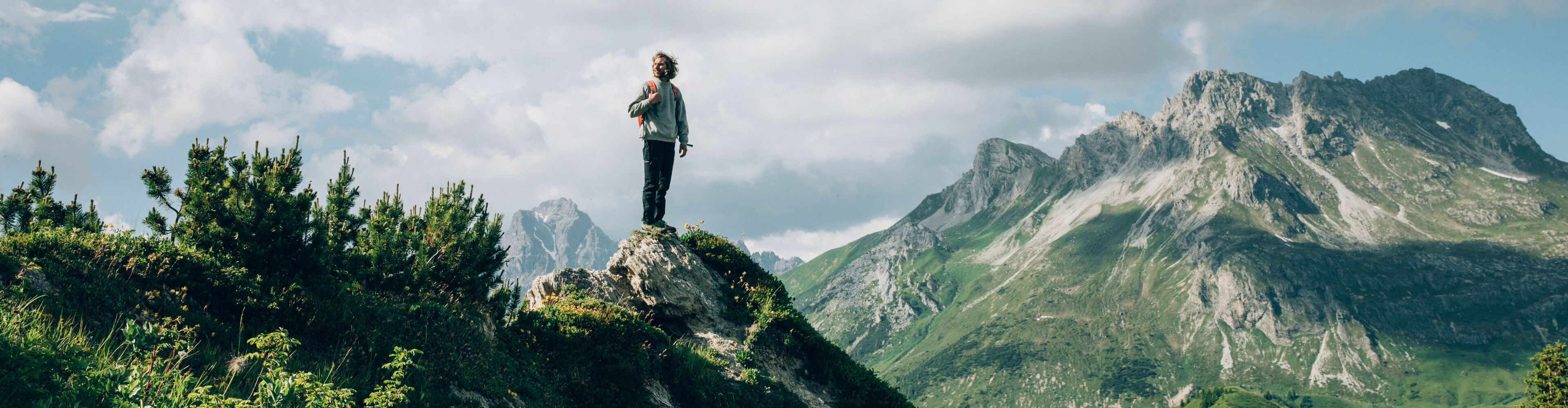 ein Wanderer steht auf einem Felsvorsprung und genießt die Aussicht auf die Gipslöcher und das traumhafte Bergpanorama im Hintergrund