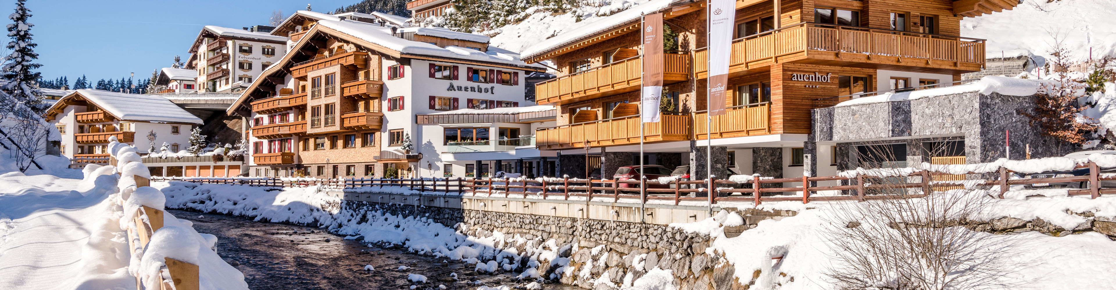 Blick auf den Auenhof im Winter, im Vordergrund fließt die Lech durch