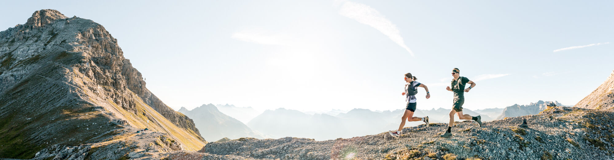 Zwei Trailrunner laufen entlang des Mohnensattel mit Blick auf die Mohnenfluh
