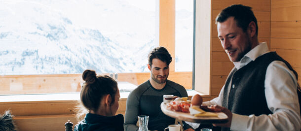 Ein Kellner bringt eine Frühstücksplatte zu den Gästen an den Tisch Ein Kellner bringt eine Frühstücksplatte zu den Gästen an den Tisch