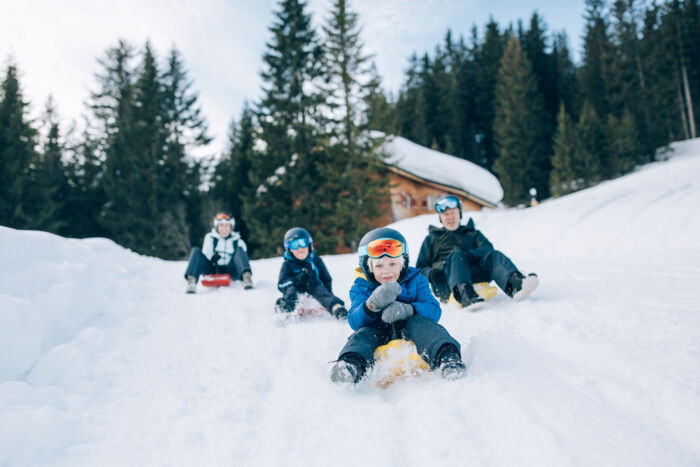 eine Familie rodelt über die Rodelbahn in Lech Zürs mit dem Zipfelbob hinunter
