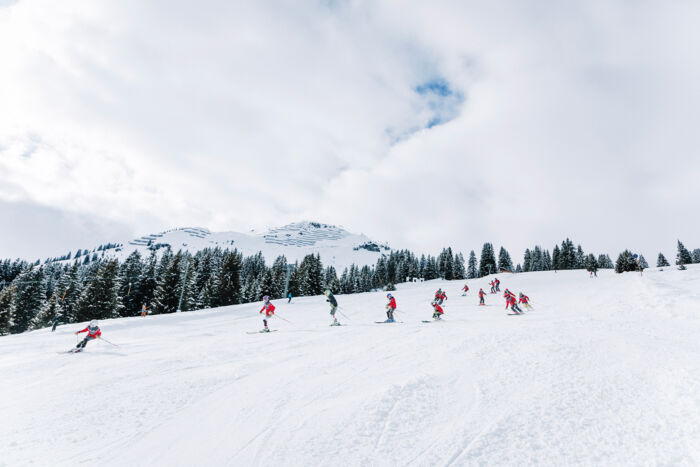 Skiclubkinder fahren hintereinander die Piste hinunter