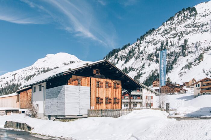 Blick auf das Lechmuseum im Winter, wo im Hintergrund die verschneite Bergkulisse zu sehen ist