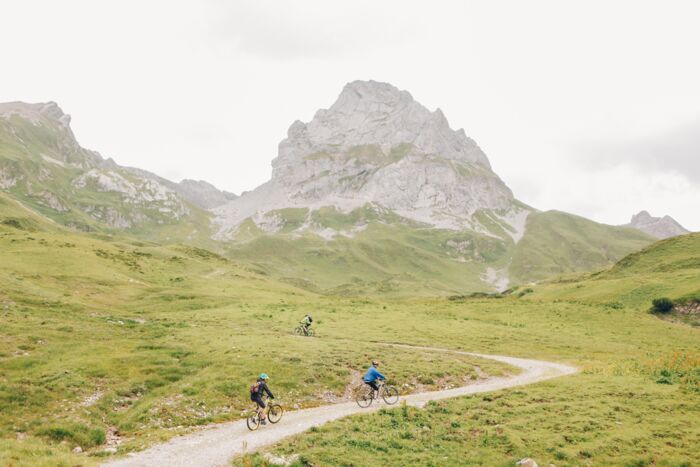 Drei Radfahrer fahren einen Schotterweg auf einen Berg hinauf.