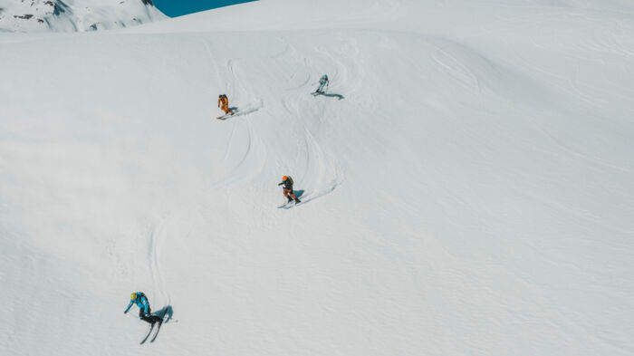 mehrere Personen fahren über die Skipiste