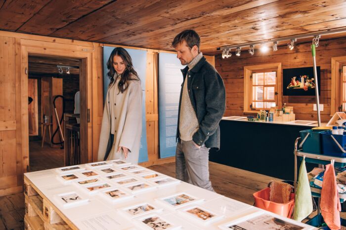 zwei Personen schauen sich gespannt die Ausstellung zu Geschichte, Kunst und Kultur an, in einem urigen, holzigen Ambiente